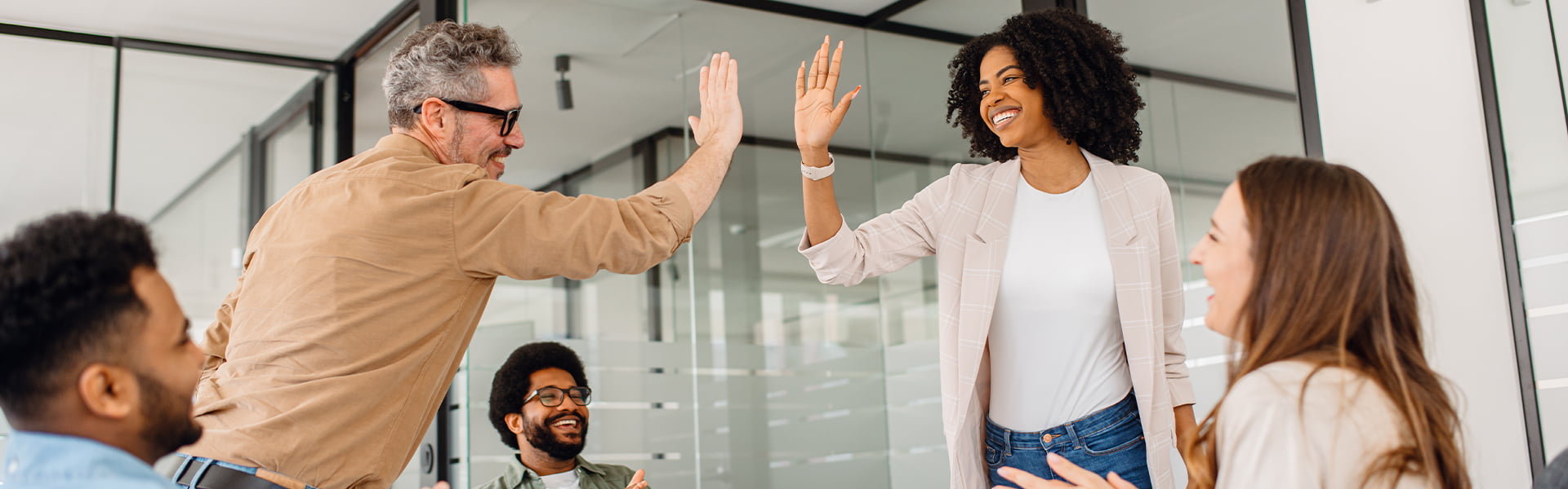 Two people high fiving while three others watch and smile