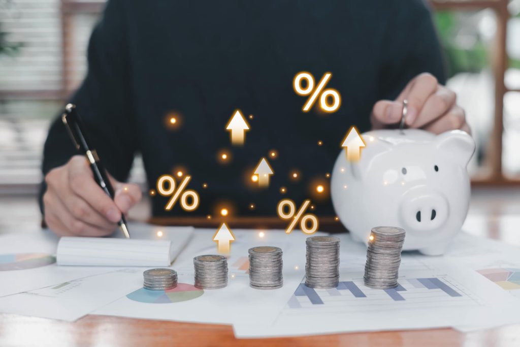A person putting a coin in a piggy bank with arrows graphically added onto the screen pointing upward
