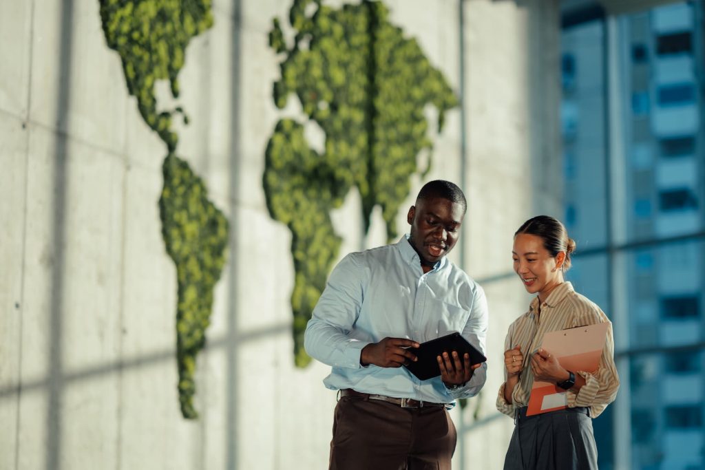 Two office workers standing in a modern office building looking over a tablet